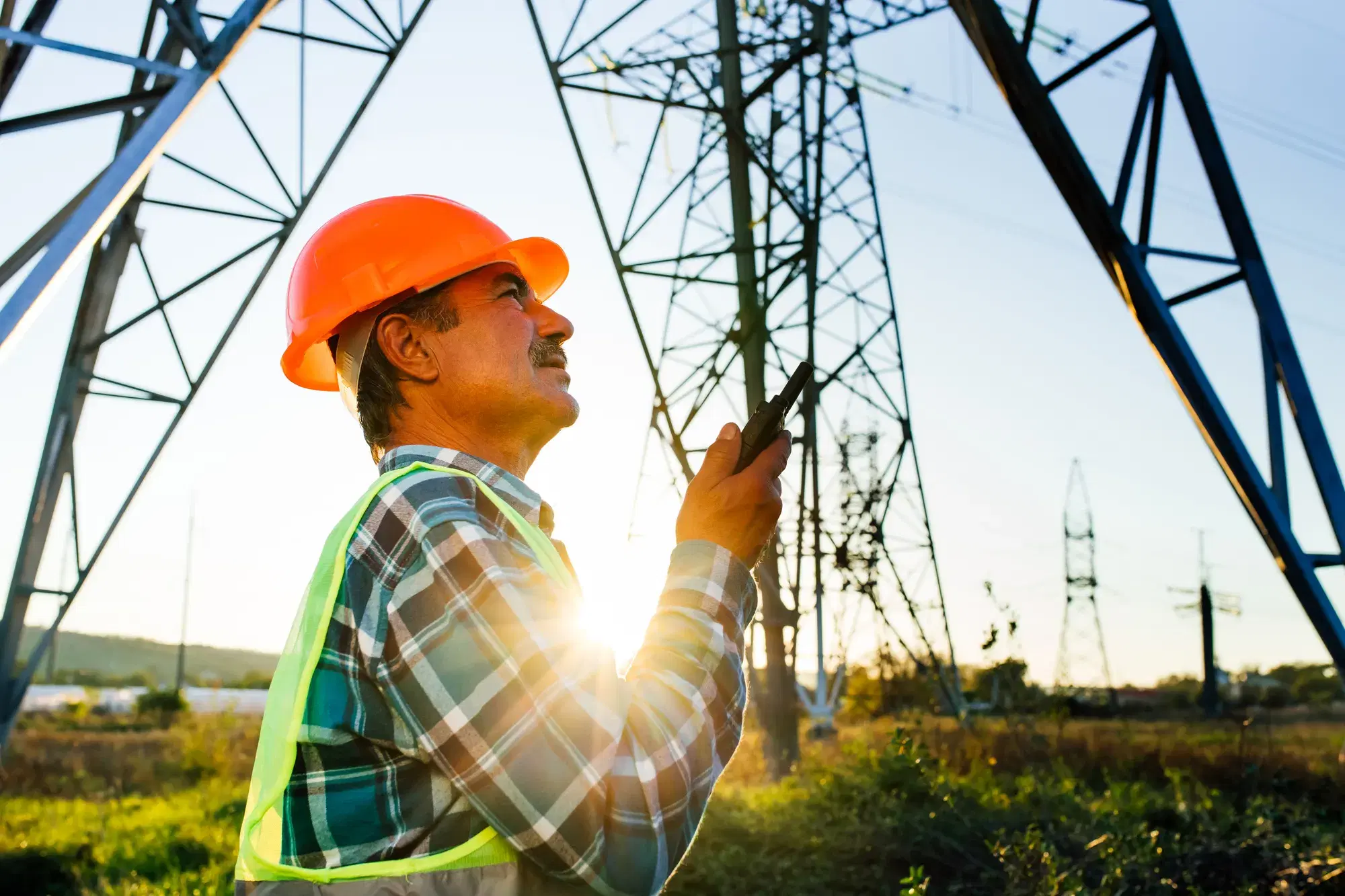 Engineer inspecting a transmission line at sunrise